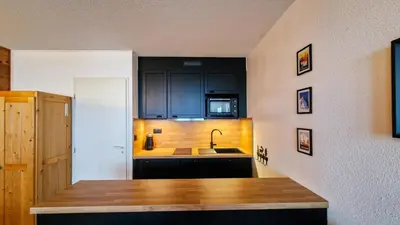 a kitchen with black cabinets and a sink at Résidence Chateaux De Crans - Studio lumineux · Balcon MAE-8264 in Magland