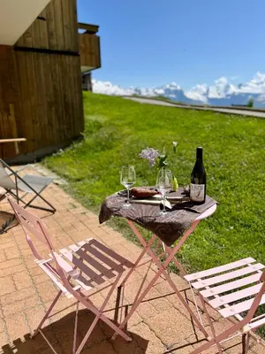 a table with two chairs and a bottle of wine at Samoens 1600, ski au pied in Samoëns