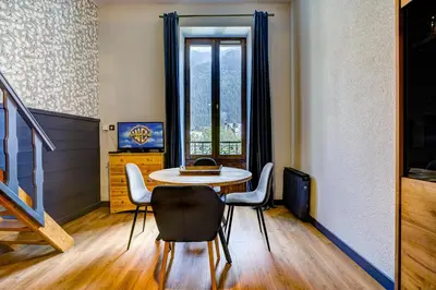 a dining room with a table and chairs and a window at Superbe appartement hyper-centre in Chamonix-Mont-Blanc