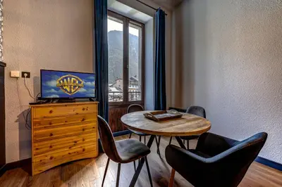 a living room with a table and chairs and a television at Superbe appartement hyper-centre in Chamonix-Mont-Blanc