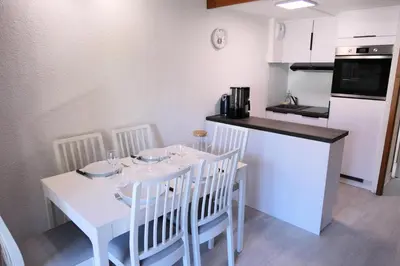 a kitchen with a white table and white chairs and a counter at Résidence Hameau De Coterat - Hameau de Coterat 11 MAE-2524 in Saint-Gervais-les-Bains