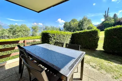 a table and chairs on a patio with bushes at Horizon Blanc in Combloux