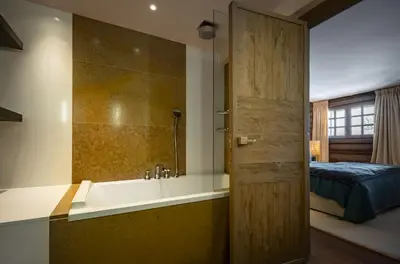 a bathroom with a bath tub and a bed at Chalet Apollo in Megève