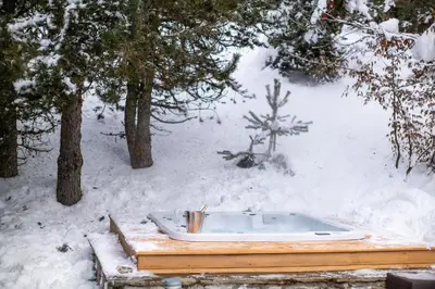 a hot tub sitting on a wooden platform in the snow at Chalet Apollo in Megève