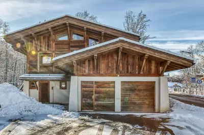 a log house with a garage in the snow at Chalet Eisstock in Megève