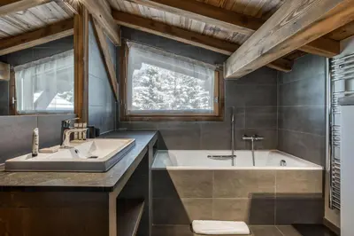 a bathroom with a sink and a tub and a window at Chalet Eisstock in Megève