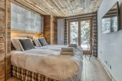 a large bed in a room with wooden walls at Chalet Eisstock in Megève