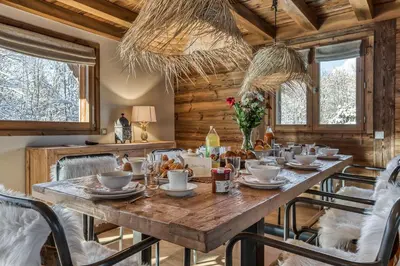 a dining room with a large wooden table and chairs at Chalet Eisstock in Megève