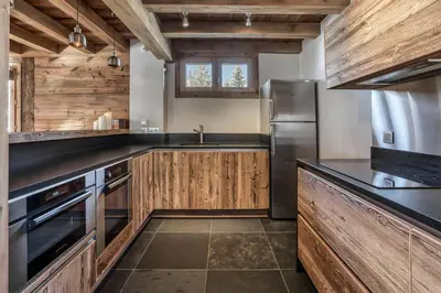 a kitchen with wooden cabinets and a stainless steel refrigerator at Chalet Eisstock in Megève