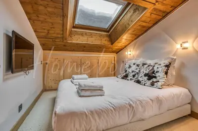 a bedroom with a large bed with a skylight at Yupik in Megève