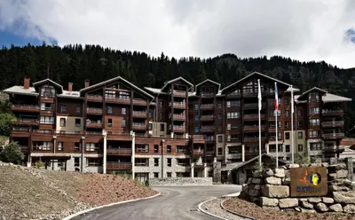 a large apartment building on a hill next to a road at Résidence Les Terrasses D'eos - Appartement confortable · Accès direct aux pistes · Piscine · Spa · WIFI gratuit et illimité MAE-6164 in Magland