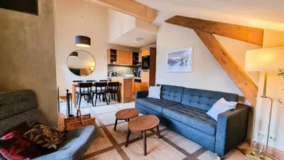a living room with a blue couch and a kitchen at Résidence Les Terrasses D'eos - Appartement confortable · Accès direct aux pistes · Piscine · Spa · WIFI gratuit et illimité MAE-6164 in Magland