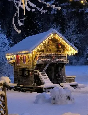 a gingerbread house with lights on it in the snow at Amour & Chocolat in Sixt