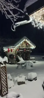 a house covered in snow with lights in the background at Amour & Chocolat in Sixt