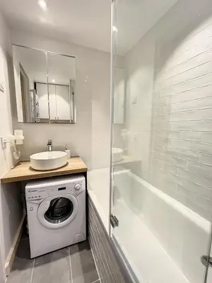 a bathroom with a washing machine and a bath tub at Superbe studio refait à neuf et tout équipé avec parking in Chamonix-Mont-Blanc