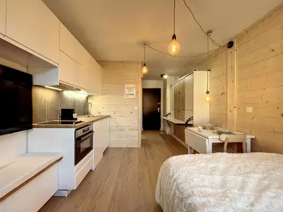 a kitchen with white cabinets and a bed in a room at Superbe studio refait à neuf et tout équipé avec parking in Chamonix-Mont-Blanc