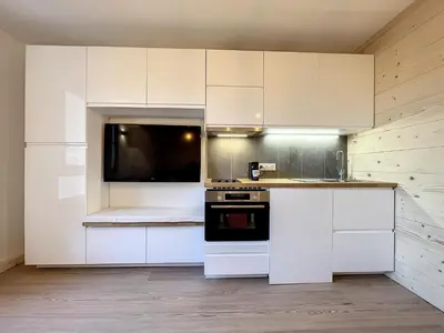 a kitchen with white cabinets and a stove top oven at Superbe studio refait à neuf et tout équipé avec parking in Chamonix-Mont-Blanc