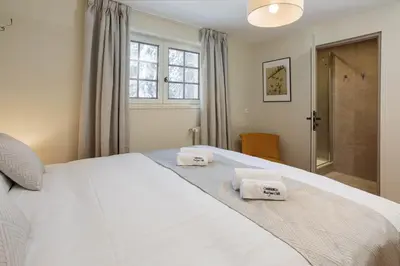 two beds in a bedroom with windows and towels at Chalet le Tricouni in Chamonix-Mont-Blanc