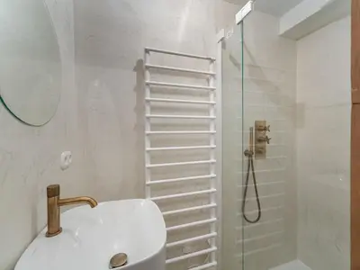 a bedroom with a bed and a door leading to a bathroom at Duplex rénové au cœur de Megève, 3 chambres, cheminée, terrasse, équipements modernes. - FR-1-569-72 in Megève