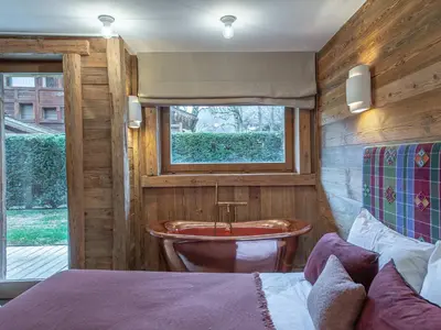a bedroom with a tub and a bed and a window at Duplex rénové au cœur de Megève, 3 chambres, cheminée, terrasse, équipements modernes. - FR-1-569-72 in Megève