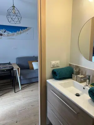 a bathroom with a sink and a living room at Charmant studio Saint Gervais 74 in Saint-Gervais-les-Bains