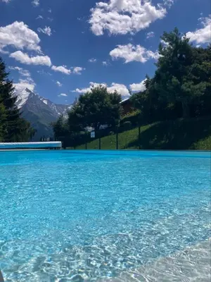 a large pool of blue water with mountains in the background at Le cocon du Bettex 1400 - Cozy Apt near Mont Blanc in Saint-Gervais-les-Bains