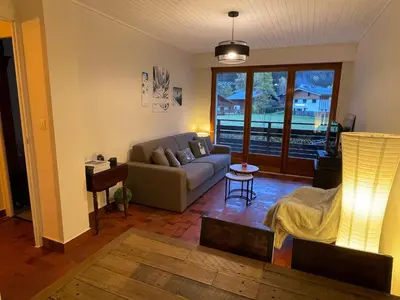 a living room with a couch and a table at Résidence Bois du Bouchet, appartement vue montagne, calme, parking gratuit, proche centre in Chamonix-Mont-Blanc