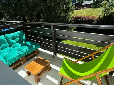 a patio with a couch and a table and chairs at Résidence Bois du Bouchet, appartement vue montagne, calme, parking gratuit, proche centre in Chamonix-Mont-Blanc