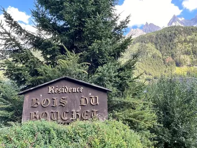 a sign in front of some trees and a mountain at Résidence Bois du Bouchet, appartement vue montagne, calme, parking gratuit, proche centre in Chamonix-Mont-Blanc