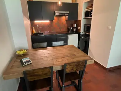 a kitchen with a wooden table and some chairs at Résidence Bois du Bouchet, appartement vue montagne, calme, parking gratuit, proche centre in Chamonix-Mont-Blanc