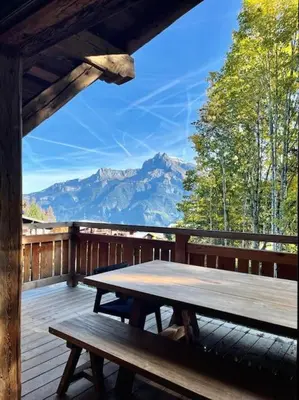 a picnic table on a deck with a view of mountains at Chalet de luxe sur les pistes - 5 chambres in Combloux
