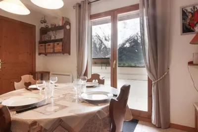 a dining room with a table and a large window at Betulle - 2bedroom - Patio facing Mont-Blanc range in Les Houches