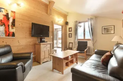 a living room with a couch and a flat screen tv at Betulle - 2bedroom - Patio facing Mont-Blanc range in Les Houches