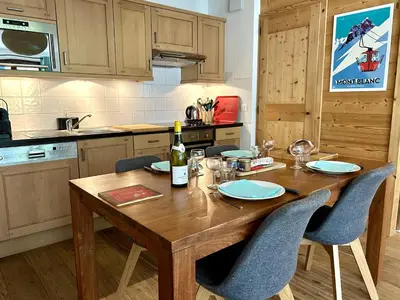a kitchen with a wooden table with chairs and a bottle of wine at Chez Charles I Vallorcine Viachamonix in Vallorcine