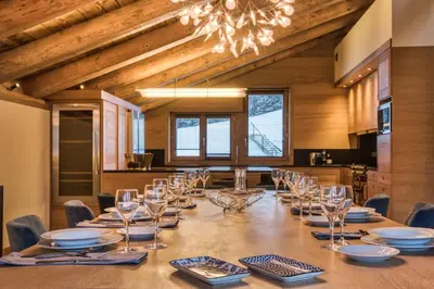a dining room with a long table with chairs and a chandelier at Rock and Stars Megève in Megève