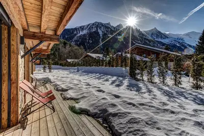 a wooden deck with a chair on top of a mountain at Chalet Red Fox in Chamonix-Mont-Blanc