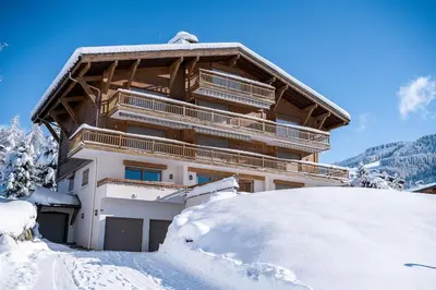a building covered in snow with a pile of snow at Flat Simba - Megève - Mont d'Arbois in Megève