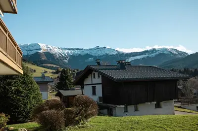 a house with snow covered mountains in the background at Flat Simba - Megève - Mont d'Arbois in Megève