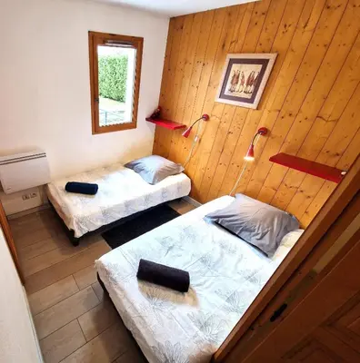two beds in a room with wooden walls at L'Appart de Chacha 2ch, 4pers Centre de Chamonix in Chamonix-Mont-Blanc