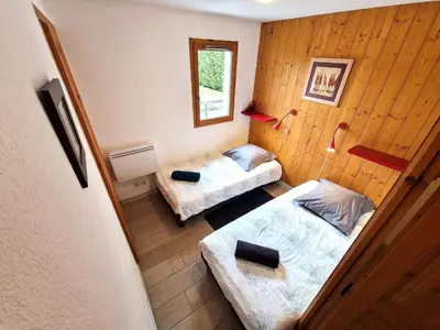 a small room with two beds and a mirror at L'Appart de Chacha 2ch, 4pers Centre de Chamonix in Chamonix-Mont-Blanc