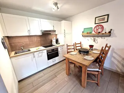 a kitchen with a wooden table with chairs and a sink at L'Appart de Chacha 2ch, 4pers Centre de Chamonix in Chamonix-Mont-Blanc