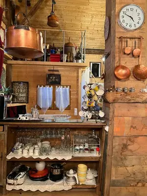 a kitchen with a clock and a shelf with dishes at Ferme savoyarde rénovée 2 chambres in Les Carroz d'Araches