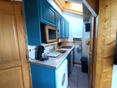 a small kitchen with blue cabinets and a sink at Cocon familial proche télécabine in Saint-Gervais-les-Bains