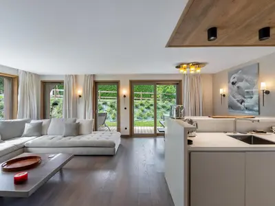 a living room with a white couch and a kitchen at Appartement Neuf, Jardin Privé, 3 Chambres, Megève Mont d'Arbois - FR-1-569-73 in Megève