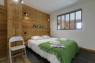 a bedroom with a bed with a chair and a window at Appartement Flégère et Golf - Happy Rentals in Chamonix-Mont-Blanc
