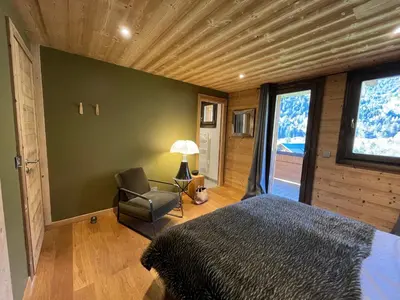 a bedroom with a bed and a chair and a window at Chalet les 3 cerfs in Les Contamines-Montjoie