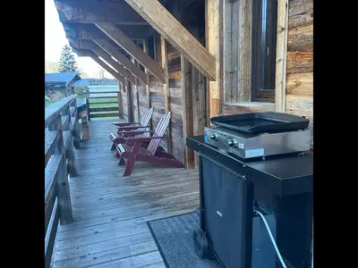 a porch of a cabin with a stove and chairs at Chalet les 3 cerfs in Les Contamines-Montjoie