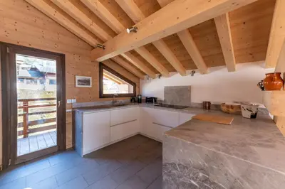 a kitchen with white cabinets and a wooden ceiling at Chalet les 3 cerfs in Les Contamines-Montjoie
