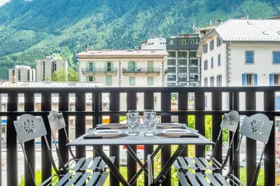 a table and chairs on a balcony with a view at Superbe appartement avec parking gratuit en centre ville et aux pieds des pistes in Chamonix-Mont-Blanc