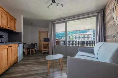 a living room with a couch and a large window at Superbe appartement avec parking gratuit en centre ville et aux pieds des pistes in Chamonix-Mont-Blanc
